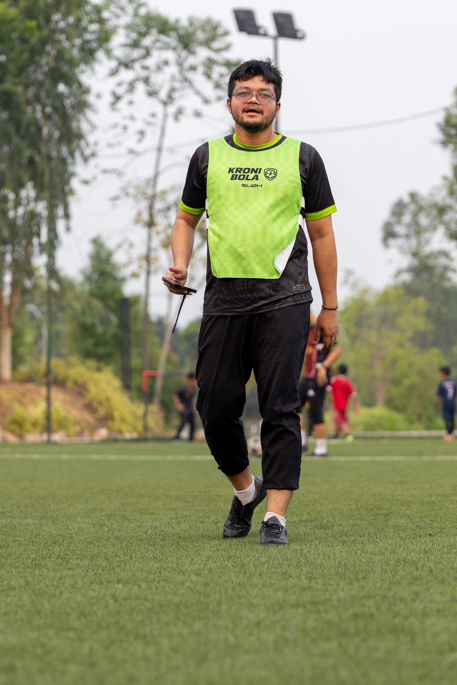 A KroniBola player in a green club bib on the pitch at Elmina